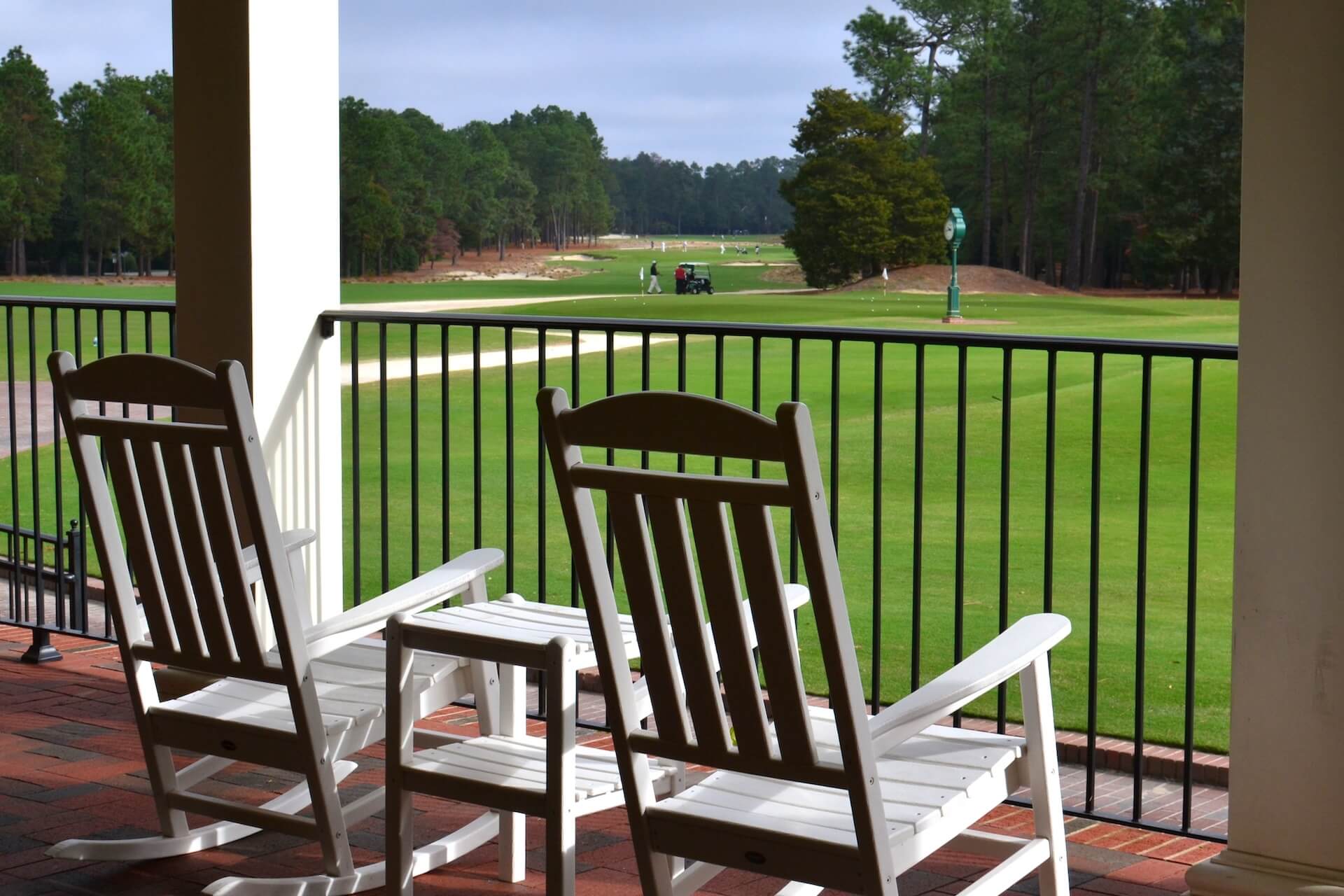 Open space living - porch with white rocking chairs overlooking a golf course | Featured image for the Elevated Living information video blog from Brookwater Residential.